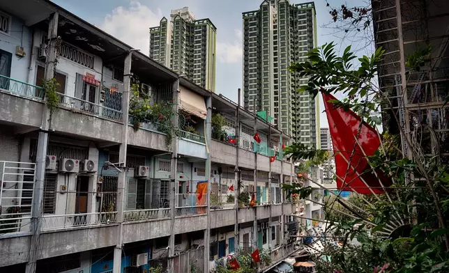 High-rise buildings tower over an aging apartment building displaying Vietnamese flags in the Cholon district of Ho Chi Minh City, Vietnam, Tuesday, April 29, 2025, ahead of the 50th anniversary of the end of the Vietnamese War. (AP Photo/Richard Vogel)