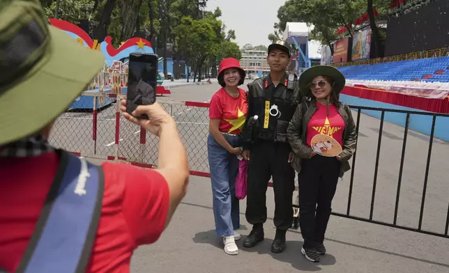 People take photos with a security officer at the venue for a parade to be held on April 30 to celebrate the 50th anniversary of the end of the Vietnam War in Ho Chi Minh City, Vietnam Tuesday, April 29, 2025. (AP Photo/Hau Dinh)
