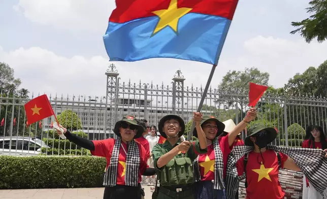 People wave Vietnamese flags and the flag of the former National Liberation Front (NLF) to celebrate the 50th anniversary of the end of the Vietnam War in front of the Independence Palace in Ho Chi Minh City, Vietnam Tuesday, April 29, 2025. (AP Photo/Hau Dinh)
