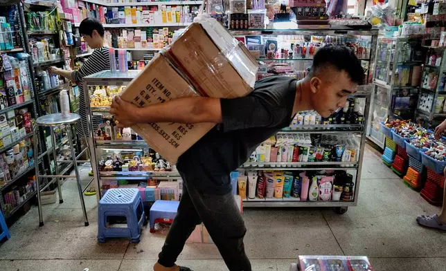 A vendor prepares her shop of various sundry items as a worker carries imported goods into the Cholon market in Ho Chi Minh City, Vietnam, on Tuesday, April 29, 2025 ahead of national celebration of the 50th Anniversary of reunification and the end of the Vietnam War. (AP Photo/Richard Vogel)