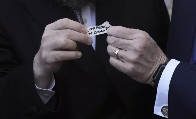 The US ambassador to Israel Mike Huckabee holds a note given to him from US President Donald Trump to be placed in the cracks of the Western Wall, the holiest site where Jews can pray, in the Old City of Jerusalem, Friday, April 18, 2025. (AP Photo/Leo Correa)