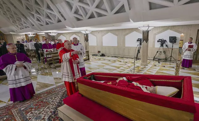 Cardinal Camerlengo Kevin Joseph Farrell, center, flanked by Master of Ceremonies Archbishop Diego Giovanni Ravelli, left, and Master of Ceremonies Lubomir Welnitz, right, performes the ceremonial aspersion of the body of Pope Francis with holy water as part of the final rites inside his private chapel at the Vatican, Monday, April 21, 2025. (Vatican Media via AP, HO)
