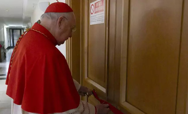 This image distributed by Vatican Media on Tuesday, April 22, 2025, shows Cardinal Camerlengo Kevin Joseph Farrell sealing Pope Francis's private apartment inside the 'Domus Sanctae Marthae' hotel at the Vatican. (Vatican Media via AP, HO)