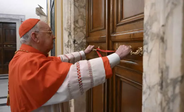 Cardinal Camerlengo Kevin Joseph Farrell seals the door to the papal bedroom and studio at the Vatican after the announcement of the death of Pope Francis, Monday, April 21, 2025. (Vatican Media via AP, HO)