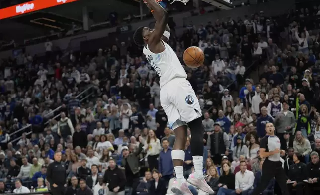 Minnesota Timberwolves guard Anthony Edwards hangs from the rim after making a basket during the first half of an NBA basketball game against the Brooklyn Nets, Friday, April 11, 2025, in Minneapolis. (AP Photo/Abbie Parr)