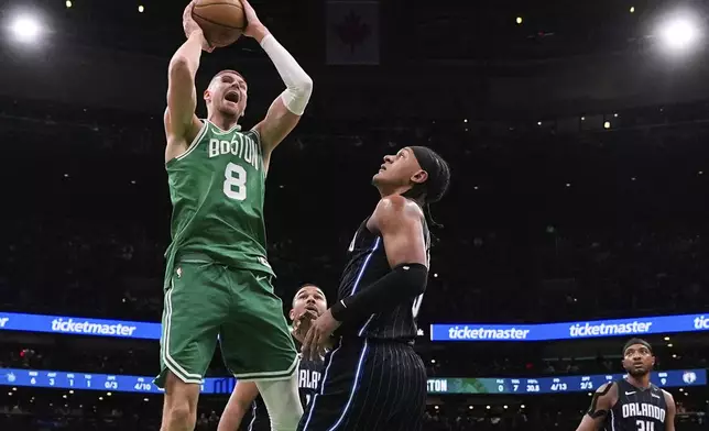Boston Celtics center Kristaps Porzingis (8) grabs a rebound against Orlando Magic forward Paolo Banchero, right, during the first half in game 2 of a first-round NBA playoff basketball series, Wednesday, April 23, 2025, in Boston. (AP Photo/Charles Krupa)