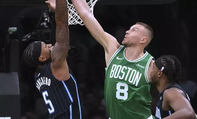 Boston Celtics center Kristaps Porzingis (8) blocks a shot by Orlando Magic forward Paolo Banchero (5) during the first half in game 2 of a first-round NBA playoff basketball series, Wednesday, April 23, 2025, in Boston. (AP Photo/Charles Krupa)