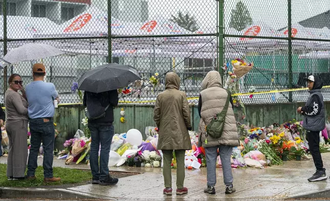 Members of the Filipino community gather at a memorial site, where tents from the Lapu Lapu festival remain up behind police lines, for the victims of an incident where a car drove through a crowd killing multiple people in Vancouver, British Columbia, Monday April 28, 2025. (Rich Lam/The Canadian Press via AP)