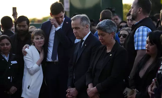 Liberal Leader Mark Carney, center, stands with members of the Filipino community alongside Mable Elmore, MLA for Vancouver Kensington, with British Columbia Premier David Eby and his wife Cailey Lynch as they visit a memorial after a vehicle drove into a crowd during a Filipino heritage festival in Vancouver, British Columbia, Sunday, April 27, 2025. (Sean Kilpatrick/The Canadian Press via AP)