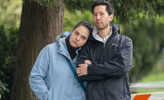 Visitors at a memorial site for the victims of an incident where a car drove through a crowd killing multiple people are overcome with emotion in Vancouver, British Columbia, Monday April 28, 2025. (Rich Lam/The Canadian Press via AP)