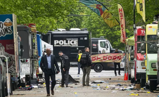 Vancouver Police detectives walk along where a car drove through a crowd killing multiple people on the weekend in Vancouver, British Columbia, Monday April 28, 2025. (Rich Lam/The Canadian Press via AP)