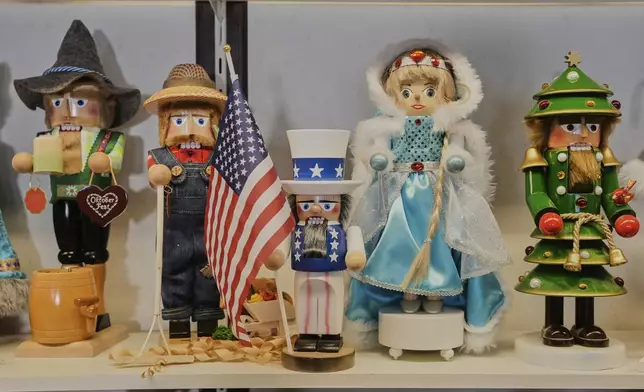 An Uncle Sam nutcracker with an American flag, center, stands between other nutcrackers at the Steinbach-Volkskunst nutcracker factory in Marienberg, Germany, Tuesday, April 15, 2025. (AP Photo/Markus Schreiber)