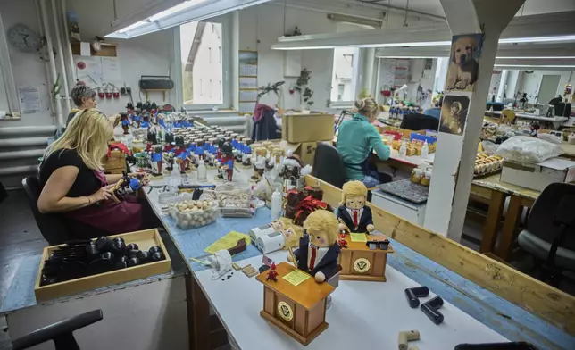 Two limited-edition nutcrackers titled "Resolute Desk of the President," featuring a seated figure signing a "presidential proclamation," are seen on a table at the Steinbach-Volkskunst nutcracker factory in Marienberg, Germany, Tuesday, April 15, 2025. (AP Photo/Markus Schreiber)