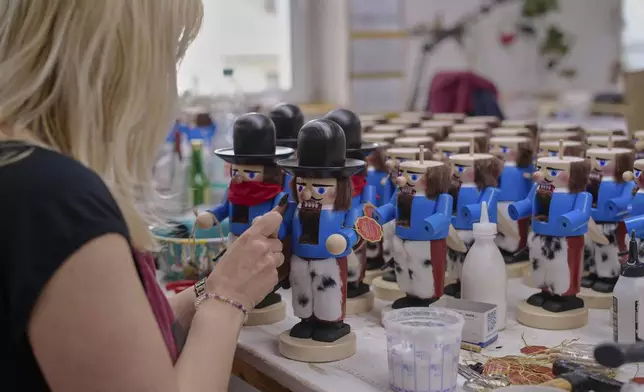 A woman works on nutcrackers of a cowboy at the Steinbach-Volkskunst nutcracker factory in Marienberg, Germany, Tuesday, April 15, 2025. (AP Photo/Markus Schreiber)