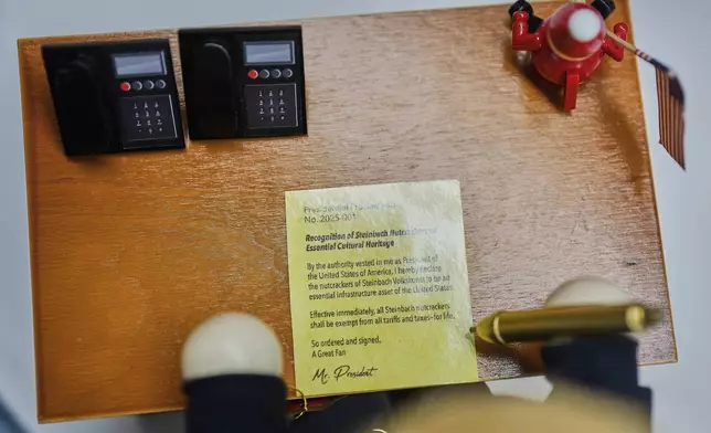 The desk of the limited-edition nutcracker titled "Resolute Desk of the President," featuring a seated figure signing a "presidential proclamation," is seen at the Steinbach-Volkskunst nutcracker factory in Marienberg, Germany, Tuesday, April 15, 2025. (AP Photo/Markus Schreiber)