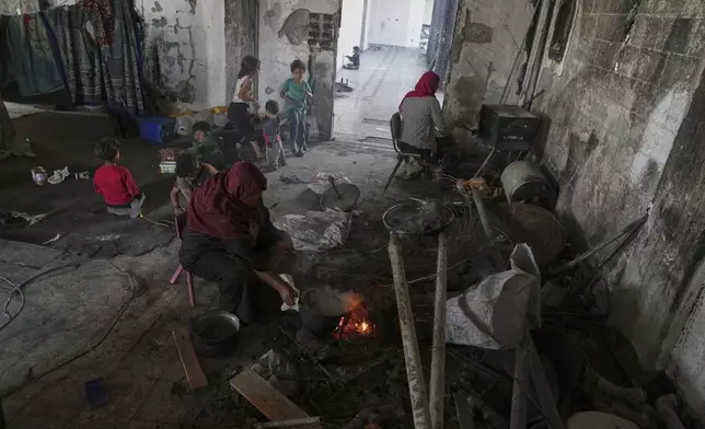 Hiam Al-Kafarna prepares food on a fire for her family at the Islamic University in Gaza City, now a shelter for displaced Palestinians amid the ongoing war in Gaza, Friday, April 4, 2025. (AP Photo/Jehad Alshrafi)
