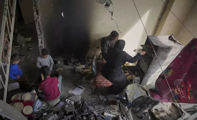 Members of the Za'anin family, displaced from Beit Hanoun, cook on an open fire at the Islamic University in Gaza City, which is now a shelter for displaced Palestinians amid the ongoing war in Gaza, Saturday, April 5, 2025. (AP Photo/Jehad Alshrafi)