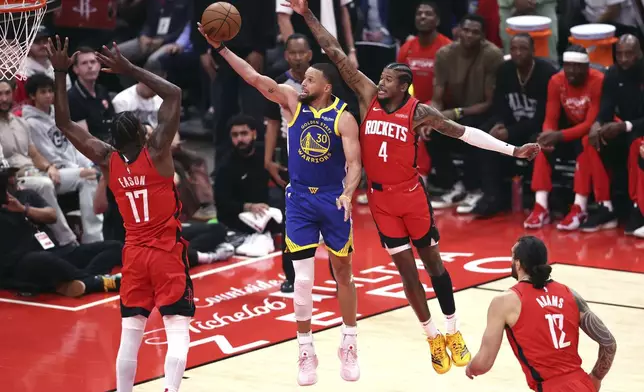 Golden State Warriors' Stephen Curry (30) scores against Houston Rockets' Tari Eason (17) and Jalen Green (4) during the first half of Game 1 of an NBA basketball first-round playoff series in Houston, Sunday, April 20, 2025. (Scott Strazzante/San Francisco Chronicle via AP)