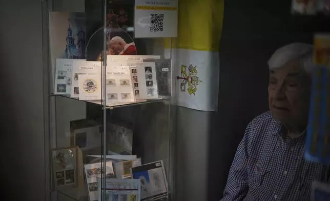 Ermenegildo Santarossa sits in his Filitalia stamps, coins, and souvenirs shop next to the Vatican walls in Rome, Tuesday, April 29, 2025. (AP Photo/Andrew Medichini)