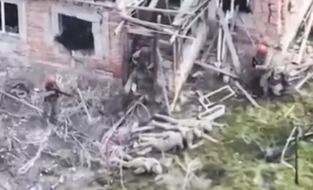 This image taken from video that European military officials say was filmed by a Ukrainian drone in the southern Ukrainian village of Piatykhatky on March 13, 2025, shows three soldiers with red helmets and uniform markings identified as Russian surrounding four Ukrainian soldiers who appear to have surrendered and are laying on the ground. (Ukraine Military/European Defense Officials via AP)