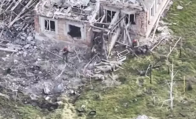 This image taken from video that European military officials say was filmed by a Ukrainian drone in the southern Ukrainian village of Piatykhatky on March 13, 2025, shows three soldiers with red helmets and uniform markings identified as Russian surrounding four Ukrainian soldiers who appear to have surrendered and are laying on the ground. (Ukraine Military/European Defense Officials via AP)