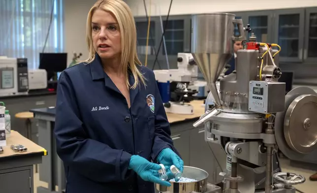 Attorney General Pam Bondi holds vials containing a genuine oxycodone pill and a counterfeit one at a Drug Enforcement Administration (DEA) research laboratory on Tuesday, April 29, 2025, in Northern Virginia. (AP Photo/Mark Schiefelbein)