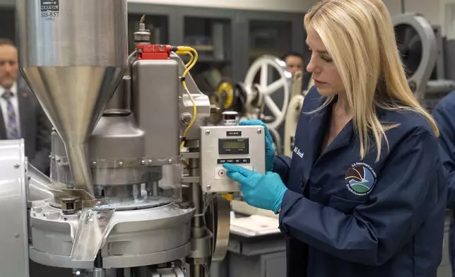 Attorney General Pam Bondi operates a a tablet press machine as it manufactures simulated fentanyl pills at a Drug Enforcement Administration (DEA) research laboratory on Tuesday, April 29, 2025, in Northern Virginia. (AP Photo/Mark Schiefelbein)