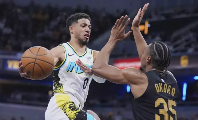 Indiana Pacers guard Tyrese Haliburton (0) makes a pass over Cleveland Cavaliers forward Isaac Okoro (35) during the second half of an NBA basketball game in Indianapolis, Thursday, April 10, 2025. (AP Photo/Michael Conroy)