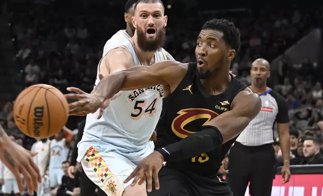 Cleveland Cavaliers guard Donovan Mitchell, right, passes the ball as he is guarded by San Antonio Spurs forward Sandro Mamukelashvili (54) during the second half of an NBA basketball game, Friday, April 4, 2025, in San Antonio. (AP Photo/Darren Abate)
