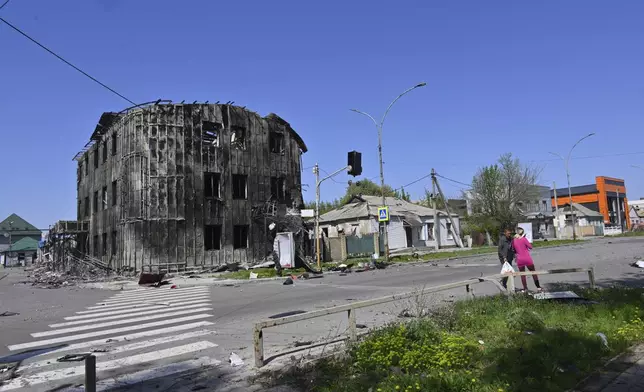 Local residents walk past damaged buildings in central Pokrovsk, the site of the heaviest battles with the Russian troops in the Donetsk region, Ukraine, Wednesday, April 23, 2025. (AP Photo/Michael Shtekel)