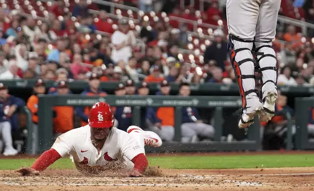 St. Louis Cardinals' Willson Contreras, left, as Houston Astros catcher Yainer Diaz leaps for the throw during the fifth inning of a baseball game Monday, April 14, 2025, in St. Louis. (AP Photo/Jeff Roberson)