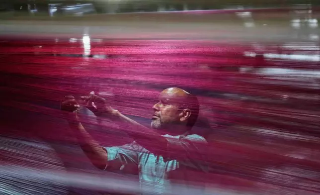 An Indian worker checks thread reels on a carpet weaving machine at a factory on the outskirts of Jammu, India, Tuesday, April 8, 2025. (AP Photo/Channi Anand)