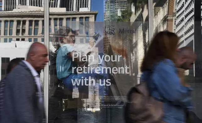 People walk past a retirement advertisement from Merrill Lynch in Los Angeles Tuesday, April 8, 2025. (AP Photo/Jae C. Hong)