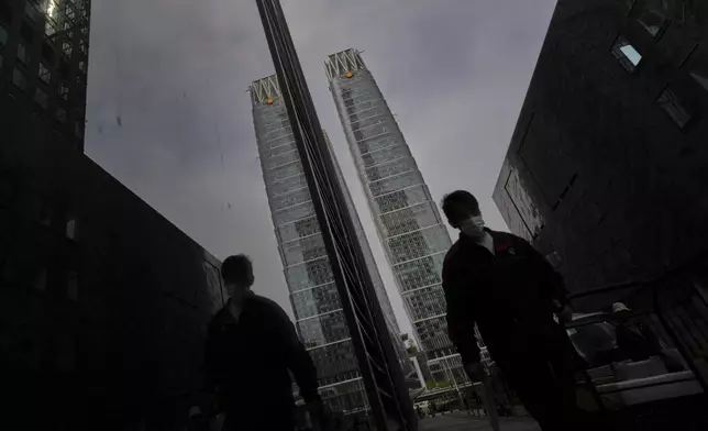 A delivery worker walks by the office buildings at the Central Business District in Beijing, Tuesday, April 8, 2025. (AP Photo/Andy Wong)
