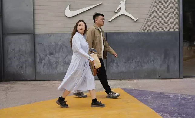 Shoppers walk near a Nike store in Beijing, China, Tuesday, April 8, 2025. (AP Photo/Ng Han Guan)