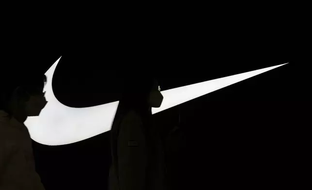 Women are silhouetted, as they walk past a Nike signage on display outside the Nike store inside a shopping mall, in Beijing, Tuesday, April 8, 2025. (AP Photo/Andy Wong)