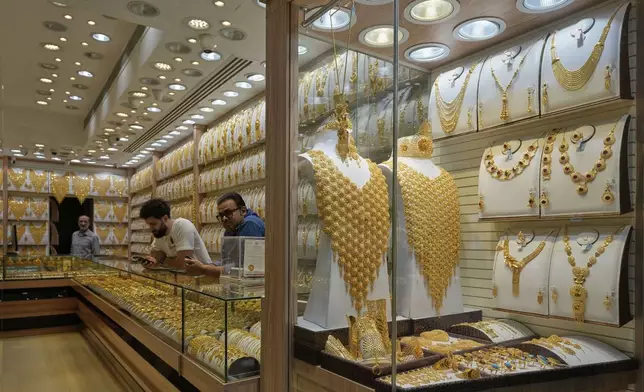 Shopkeepers wait for customers as jewelry is displayed at a jewelry shop at a gold market in Dubai, United Arab Emirates, Wednesday, April 9, 2025. (AP Photo/Altaf Qadri)