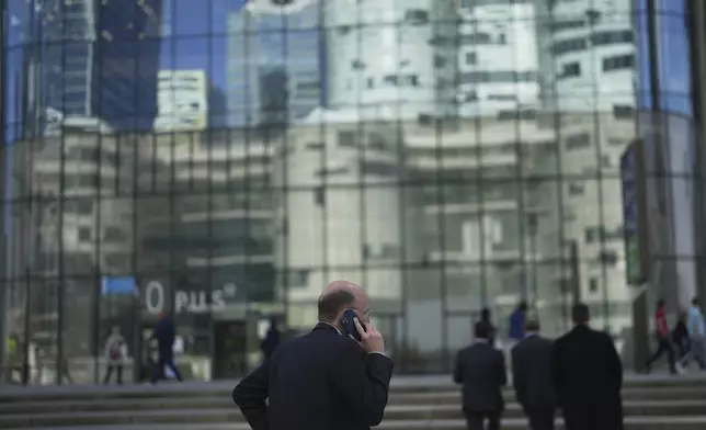 People stroll in the business district of La Defense, outside Paris, ,Tuesday, April 8, 2025. (AP Photo/Thibault Camus)
