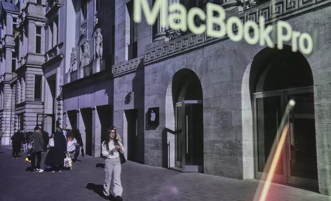 People walk outside an Apple Store in Berlin, Germany, Tuesday, April 8, 2025. (AP Photo/Ebrahim Noroozi)