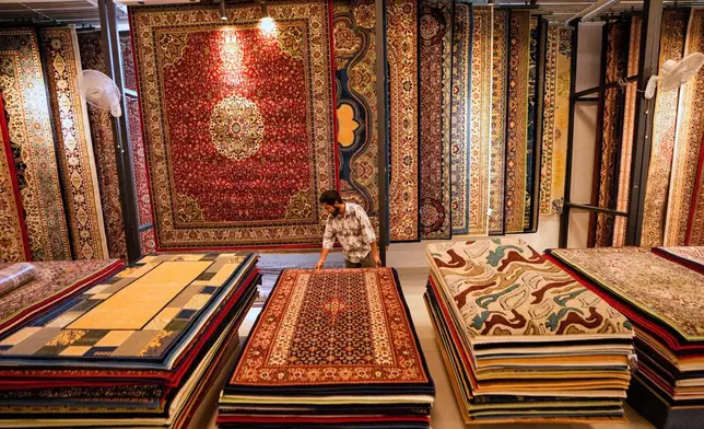 An Indian worker displays carpets at a factory on the outskirts of Jammu, India, Tuesday, April 8, 2025. (AP Photo/Channi Anand)