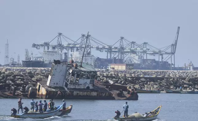 Local fishermen on their boats sail past huge cranes loading containers on to ships at a port in Chennai, India, Tuesday, April 8, 2025. (AP Photo/R. Parthibhan)