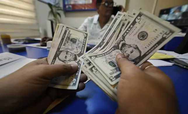 A customer counts dollars inside a forex shop in Guwahati, India, Tuesday, April 8, 2025. (AP Photo/Anupam Nath)
