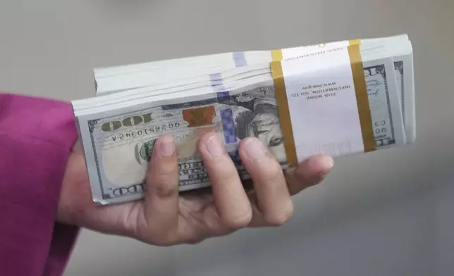 An employee holds U.S dollars banknotes at a money changer in Jakarta, Indonesia, Tuesday, April 8, 2025. (AP Photo/Tatan Syuflana)