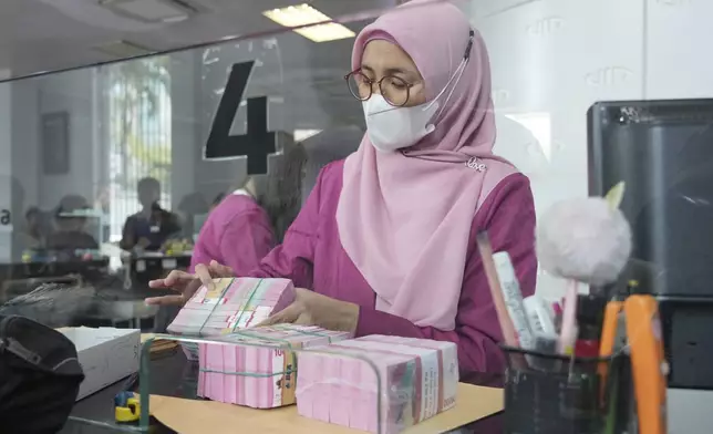 An employee counts rupiah banknotes at a money changer in Jakarta, Indonesia, Tuesday, April 8, 2025. (AP Photo/Tatan Syuflana)