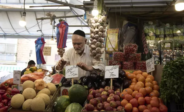 An Israeli shopkeeper places a price tag for his watermelon at his fruit and vegetable stall in the Machane Yehuda Market in Jerusalem, Israel, Tuesday, April 8, 2025. (AP Photo/Maya Alleruzzo)