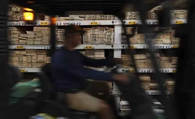 A worker drives a forklift past shelves of Canadian spruce planks, at Shell Lumber and Hardware, Tuesday, April 8, 2025, in Miami. (AP Photo/Rebecca Blackwell)
