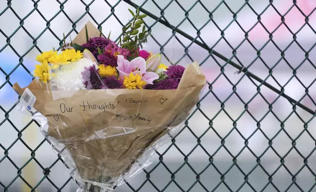 A bouquet of flowers is seen attached to a nearby fence the day after a driver killed multiple people during a Filipino community festival Sunday, April 27, 2025, in Vancouver, British Columbia. (AP Photo/Lindsey Wasson)