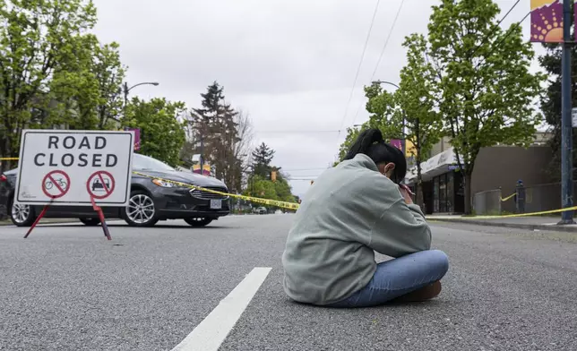 A woman sits and prays near the site where a vehicle drove into crowd at a street festival last night killing multiple people in Vancouver, British Columbia, Sunday, April 27, 2025. (Rich Lam/The Canadian Press via AP)