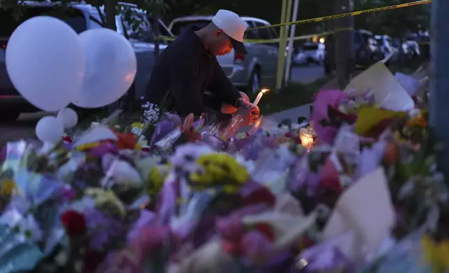 A man holds a candle at a memorial after a vehicle drove into a crowd during a Filipino heritage festival in Vancouver, British Columbia, Sunday, April 27, 2025. (AP Photo/Lindsey Wasson)