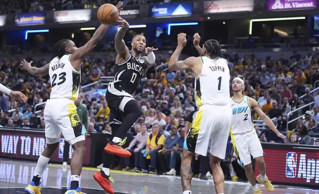 Milwaukee Bucks guard Damian Lillard (0) makes a pass between Indiana Pacers forward Aaron Nesmith (23) and forward Obi Toppin (1) during the first half of a first-round NBA basketball playoff game in Indianapolis, Tuesday, April 22, 2025. (AP Photo/Michael Conroy)